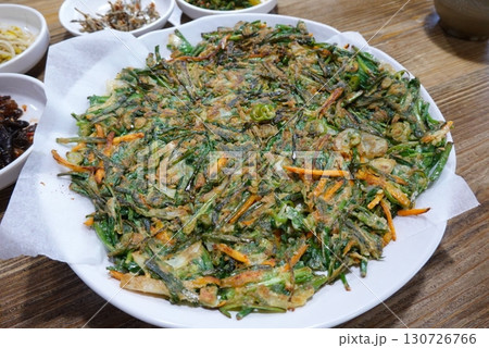 Crispy and savory Korean Pajeon, or scallion pancake, made with green onions and a variety of vegetables. A delicious, traditional Korean snack perfect for any meal. 130726766