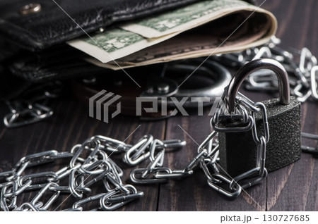 A wallet filled with money is chained in a heavy metal chain A wallet filled with money is chained in a heavy metal chain 130727685