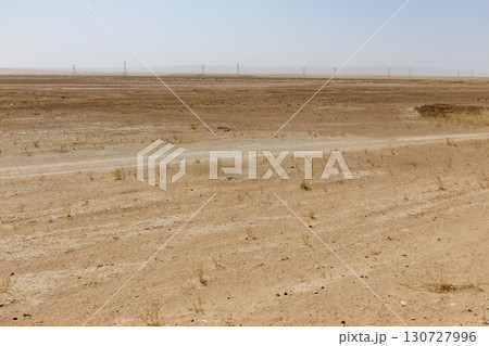 Dry desert landscape with a dirt road and power pylons in Jowzjan Province of Afghanistan Dry desert landscape with a dirt road and power pylons in Jowzjan Province of Afghanistan 130727996