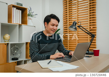 happy man working with laptop computer at home office 130728446