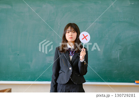 クイズに答える女子学生　学校の教室で○✕を出す教育イメージ 130729281