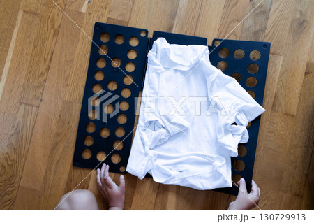 White shirt being folded on black folding board by caucasian child hands 130729913