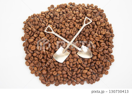 Detailed shot of crossed shovels resting on a sea of roasted coffee beans Detailed shot of crossed shovels resting on a sea of roasted coffee beans 130730413