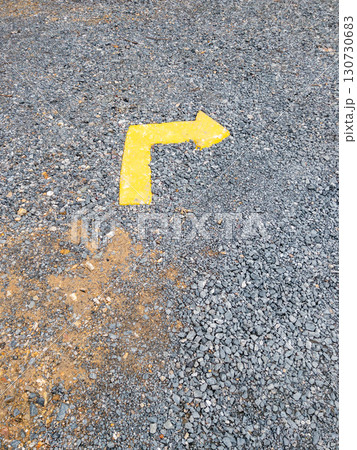 Faded Yellow Directional Arrow on Gravel. 130730683