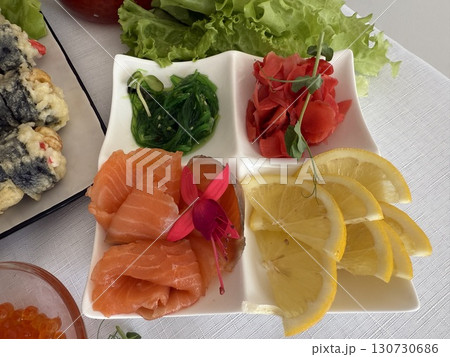 Red fish caviar swirls on the table with lemon, eco and natural dietary food. lemon wasabi ginger seaweed chuka red fish white table decorated with flowers and microgreens 130730686