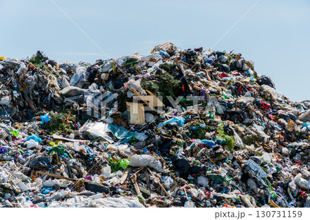 Vast mountain of accumulated mixed plastic, paper, and general waste materials. Open air landfill under bright blue sky. Severe environmental pollution. Vast mountain of accumulated mixed plastic, paper, and general waste materials. Open air landfill under bright blue sky. Severe environmental pollution. 130731159