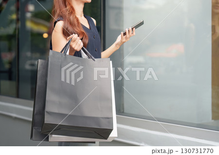 Shopping and Digital Connection. Young woman with shopping bags using smartphone. 130731770