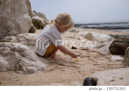 Little blonde European girl walking on an empty sandy beach in Portugal Little blonde European girl walking on an empty sandy beach in Portugal 130732261