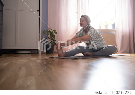 40-year-old woman doing yoga at home, stretching and hip-opening exercises 130732279