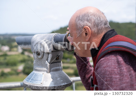 elderly man looking through tourist viewing telescope at fortress in Portugal 130732320