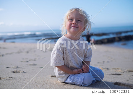 blonde three-year-old girl sitting on sandy beach in Portugal blonde three-year-old girl sitting on sandy beach in Portugal 130732321