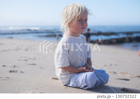 blonde three-year-old girl sitting on sandy beach in Portugal 130732322