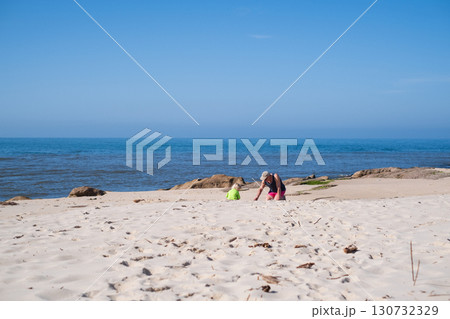 girl playing with grandfather in sand on the beach during summer holidays 130732329
