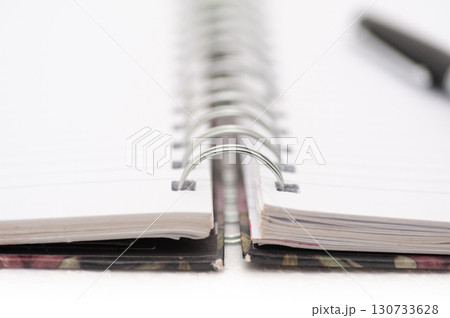 A spiral bound notebook with a pen on top of it 130733628