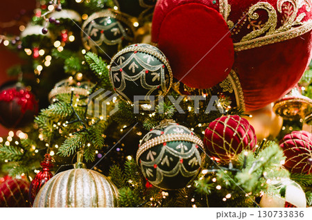 A Christmas tree with many ornaments including a red ball with a gold trim A Christmas tree with many ornaments including a red ball with a gold trim 130733836