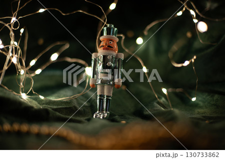 A small, wooden nutcracker is sitting on a green cloth 130733862