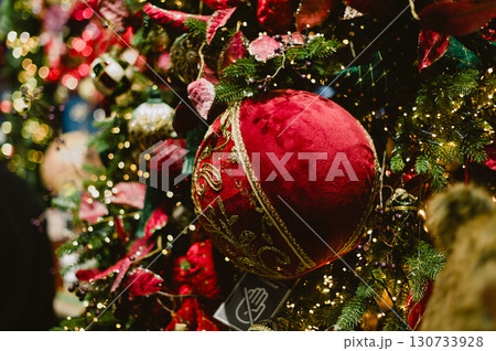 A red ball ornament hangs on a Christmas tree A red ball ornament hangs on a Christmas tree 130733928