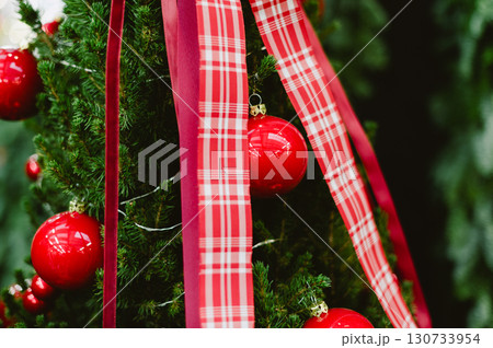 A red and white plaid ribbon is wrapped around a Christmas tree A red and white plaid ribbon is wrapped around a Christmas tree 130733954