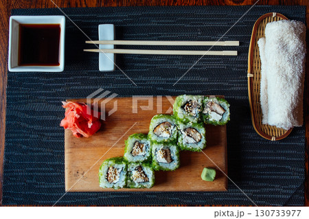 A plate of sushi with chopsticks and a small bowl of sauce A plate of sushi with chopsticks and a small bowl of sauce 130733977