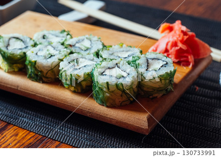 A plate of sushi with a green seaweed wrapper and a red garnish A plate of sushi with a green seaweed wrapper and a red garnish 130733991