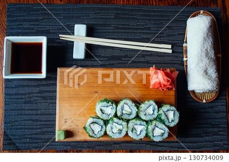 A tray of sushi with chopsticks and a dipping sauce 130734009