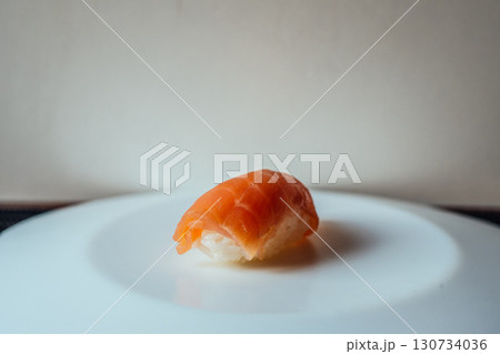 A piece of sushi is sitting on a white plate A piece of sushi is sitting on a white plate 130734036