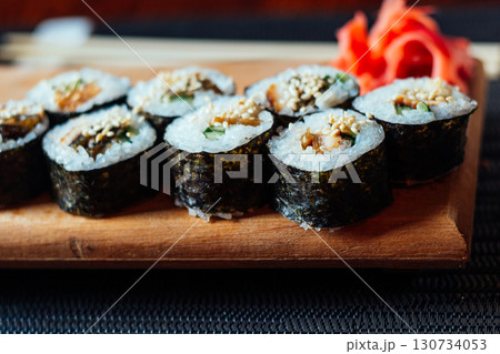 A plate of sushi with a garnish of red ginger 130734053