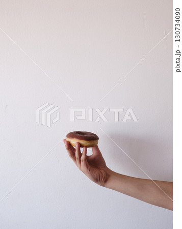 A hand holding a chocolate glazed doughnut A hand holding a chocolate glazed doughnut 130734090