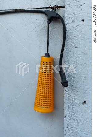 A yellow plastic container with a black cord hanging from it 130734093