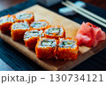 A plate of sushi with a garnish of wasabi and cucumber 130734121