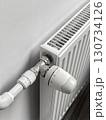 A radiator is turned off and has a white thermostat on it 130734126