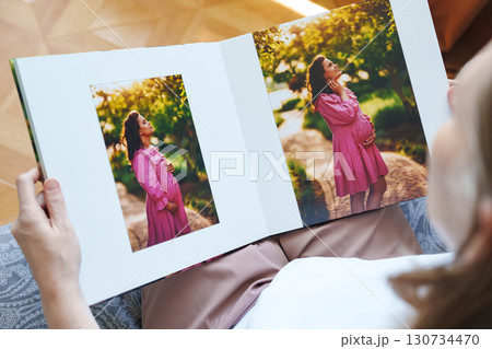 woman is holding and flipping through a photo book with a pregnancy photo shoot 130734470
