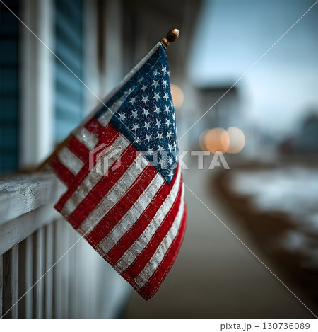 An American flag hangs simply on an outdoor railing, proudly showing its iconic stars and stripes. This patriotic symbol stands firm. 130736089
