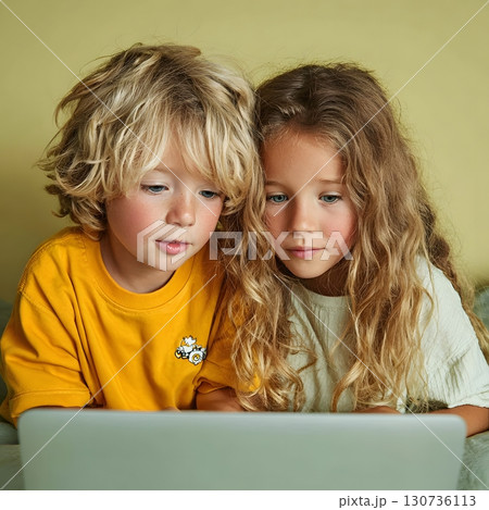 A young boy and girl are intently watching a laptop screen, learning new things and discovering digital education. 130736113