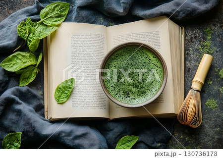 Fresh green matcha tea rests in a bowl beside a bamboo whisk, an old open book, and vibrant green leaves. Fresh green matcha tea rests in a bowl beside a bamboo whisk, an old open book, and vibrant green leaves. 130736178