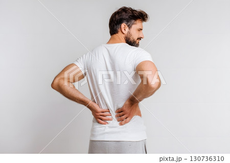 A man has back pain and holds his lower body with hands feeling discomfort. 130736310
