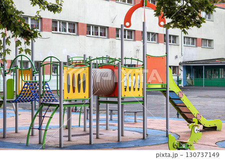 Vibrant modern playground featuring a slide, climbing net, and tunnel, offering a dynamic outdoor space for children's active play and development Vibrant modern playground featuring a slide, climbing net, and tunnel, offering a dynamic outdoor space for children's active play and development 130737149