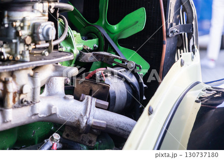 Detailed view of vintage car engine, bright green cooling fan, intricate mechanical parts, symbolizing classic automotive engineering and historical restoration 130737180