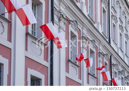 Multiple vibrant Polish flags proudly displayed on an elegant historic building facade, symbolizing national pride, patriotism, and European heritage Multiple vibrant Polish flags proudly displayed on an elegant historic building facade, symbolizing national pride, patriotism, and European heritage 130737213