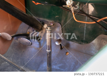 Classic vintage car interior with distinct foot pedals and a sleek chrome handbrake, highlighting the historical craftsmanship and elegant design of old automobiles 130737221