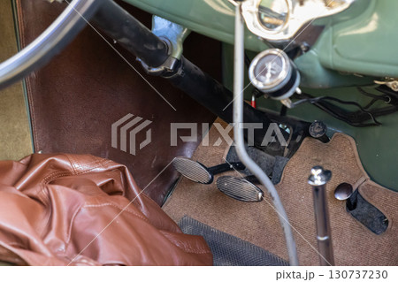 Vintage automobile interior view highlighting classic accelerator and brake pedals, steering wheel, and dashboard, capturing timeless automotive history and nostalgic travel 130737230