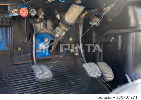Close-up view of three worn foot pedals, clutch, brake, and accelerator, inside an old manual transmission vehicle for vintage car driving 130737271