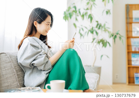 ソファに座ってスマホを見る女性 130737679