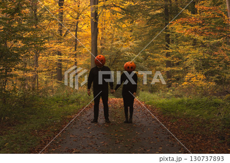Couple in Pumpkin Heads Amidst Autumn Forest 130737893