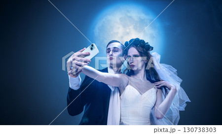 Gothic couple taking eerie selfie with smartphone under full moon Gothic couple taking eerie selfie with smartphone under full moon 130738303