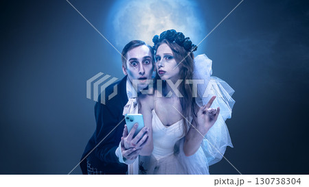 Surreal gothic couple with smartphone under moonlight in theatrical costume spooky portrait 130738304