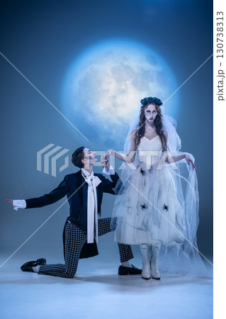 Gothic groom kneeling to pale bride in eerie moonlit ceremony 130738313