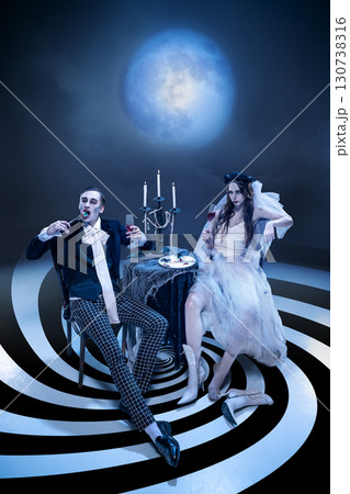 Gothic couple in eerie dinner scene with candelabra under full moon Gothic couple in eerie dinner scene with candelabra under full moon 130738316