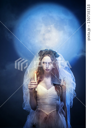 Gothic bride with black crown posing with candle in moonlight 130738318