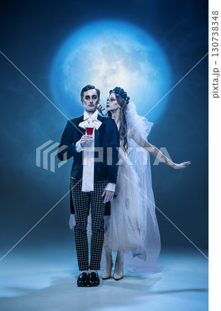 Gothic wedding couple with glass of red drink in surreal moonlit fashion scene Gothic wedding couple with glass of red drink in surreal moonlit fashion scene 130738348